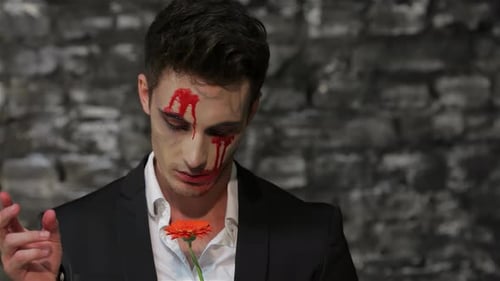 Man in Horror Make Up plucking a flower