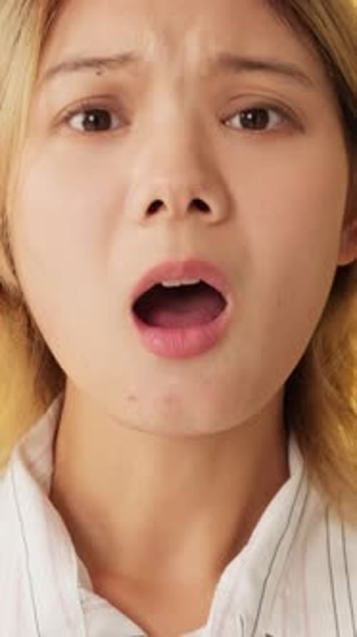 Close-up, upset young woman looking at camera isolated on yellow background in studio