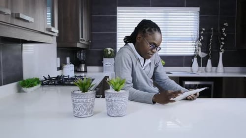 Man Uses Tablet on Kitchen Counter at Home