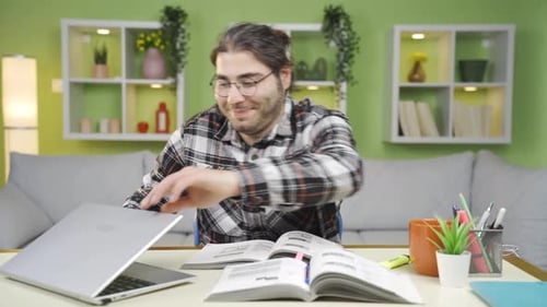 Young Adult Studying at Desk with Laptop and Book