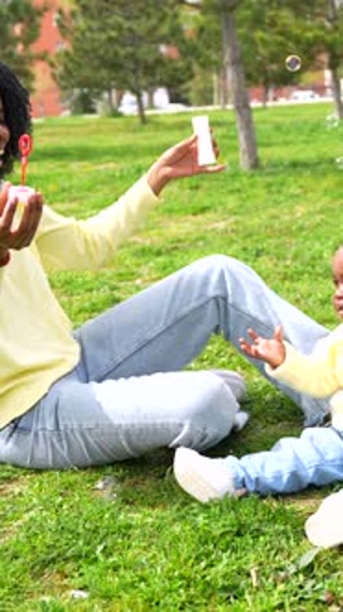 African Mother and Girl on the Park Making Soap Bubbles
