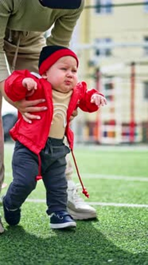 Unrecognized woman helping the toddler to walk.