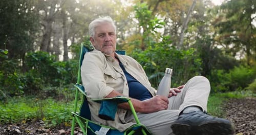Senior Man Relaxing in Chair Outdoors with Water Bottle