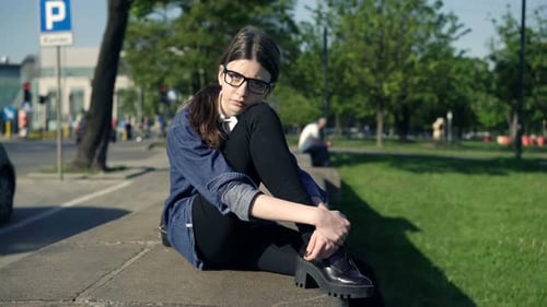 Jeune femme assise seule dans le parc de la ville en contemplant la vie par une journée de printemps ensoleillée