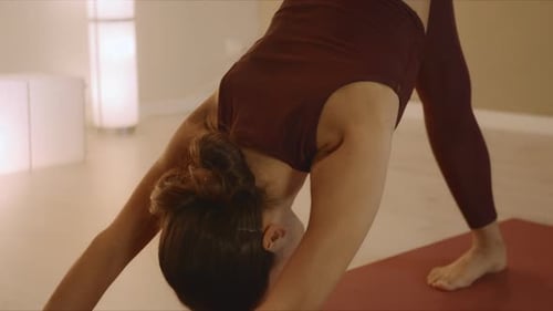 Fitness girl in one legged down dog pose on yoga mat training in studio