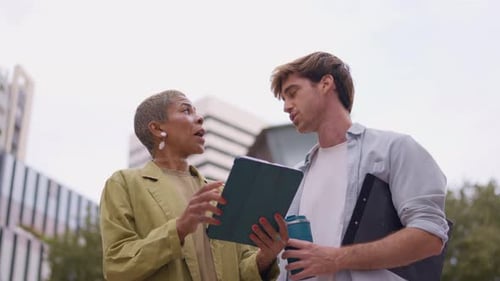 Two People Looking at a Tablet Outside