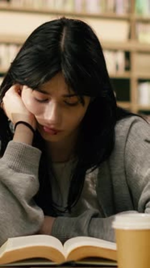 Vertical Video Stressed Woman Student Reading From Open Book Between Tall Stacks