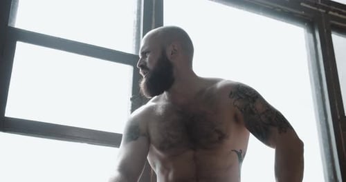 Porträt eines jungen, starken, muskulösen kaukasischen Mannes, der sich nach einem extremen Krafttraining in einem großen Fitnessstudio ausruht