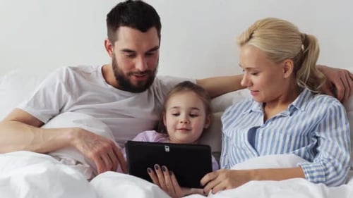 Happy Family Using Tablet Together in Bed