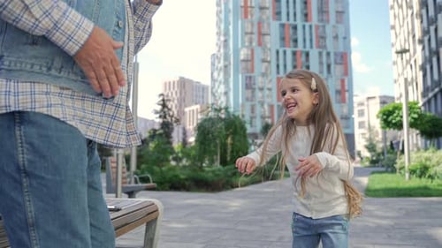 Child and Man Dancing Happily in City Park