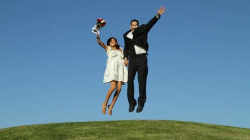 Happy Bride and Groom Jumping on Green Hill