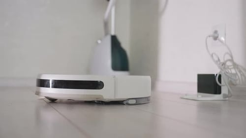 Close Up of Robot Vacuum Cleaner Moving on Wooden Floor Indoors