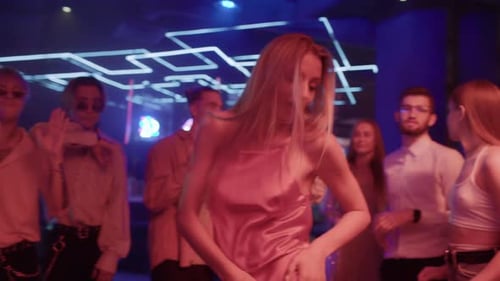 Group Of Young Friends Dances Together In Neon Light Of Night Club. Energetic Playful Moves In Di...