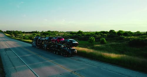 Stinger trailer with double deck car parked on country road at the sunset.