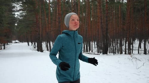 Woman Jogging Through Snowy Winter Forest