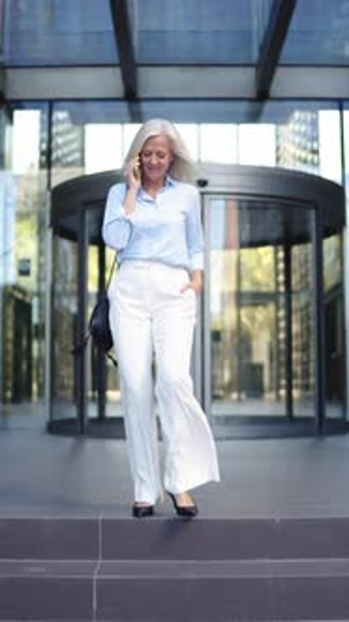 Empresária grisalha saindo da torre de escritórios durante uma conversa