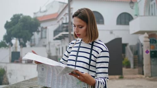 Woman Reads Map on City Street in Europe