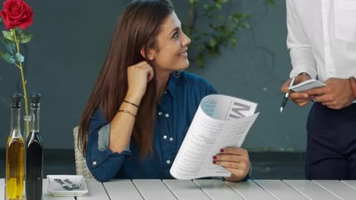 Young Independent Woman Giving Meal Order To Waiter In Cafe.