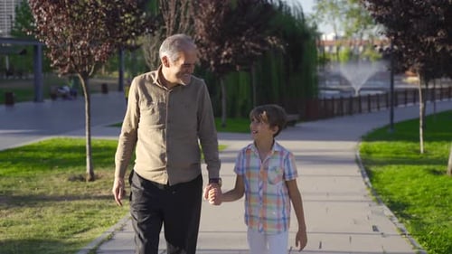 Grandfather is taking his grandson for a walk.