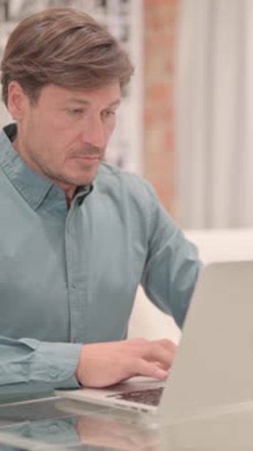 Man Typing on Laptop at Desk Indoors