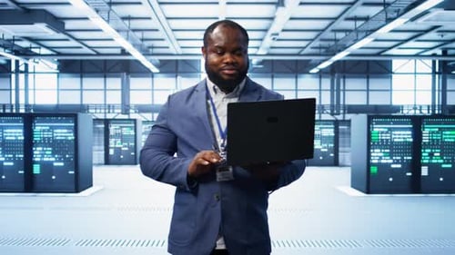 IT Engineer Working on Laptop in Data Center Overseeing Server Operations