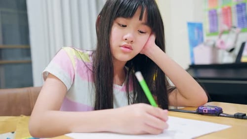 Asiatisches junges Mädchen, das am Wochenende Hausaufgaben im heimischen Wohnzimmer macht.