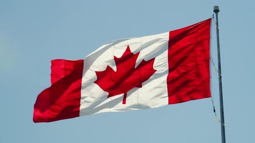 Canadian Flag Waving Against Blue Sky