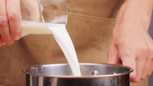 Pouring Milk in Pot Cooking Soup or Cheese Dessert