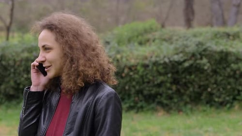 Young pretty Woman Talking On Mobile Phone In The Park