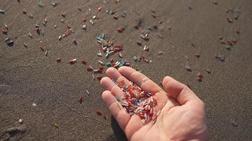Hands with Small Particles of Microplastics and Polyethylene the Problem of Water Pollution Closeup