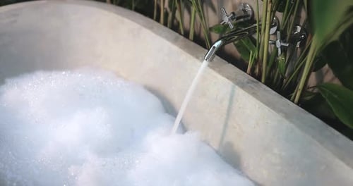 Luxurious Outdoor Stone Bathtub Filling with Foam and Running Water
