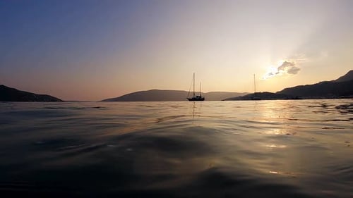 Slow motion of yacht's silhouette with a sunset sky and mountain background