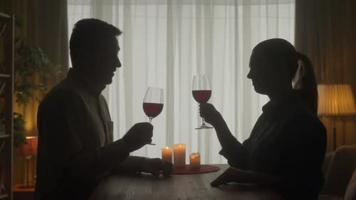 Silhouetted Couple Enjoying Romantic Wine Lit by Candles