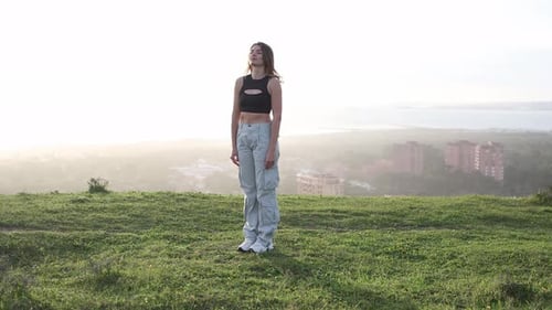 Stylish Woman Dancing Outdoors on Grassy Hill