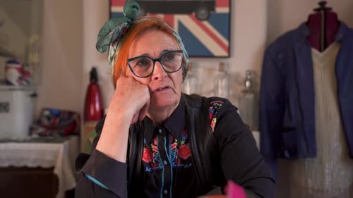 Uma senhora idosa moderna e moderna (aposentada) sentada conversando em um ambiente doméstico. Estático.