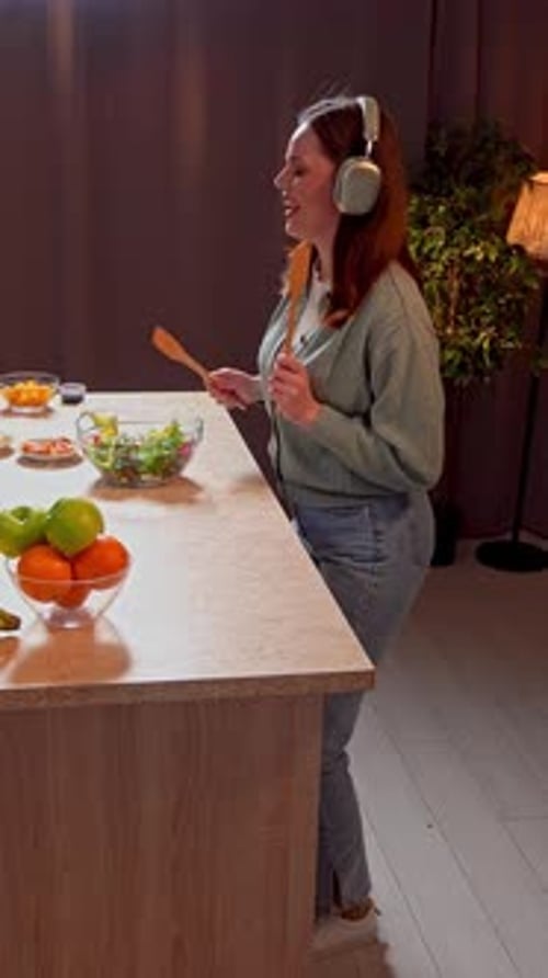 Woman Preparing Salad in Kitchen With Headphones