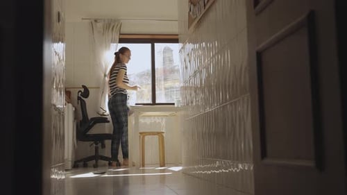 Woman Cleans Sunny Window in Bright Home