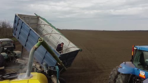Blue tractor with yellow seeder working on the field in Ukraine OA