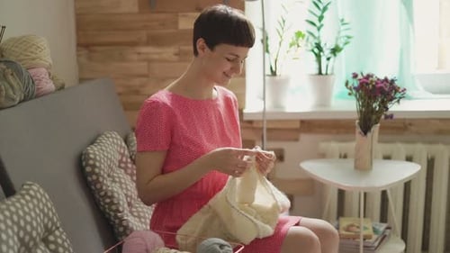 Woman knitting indoors on sofa in bright light