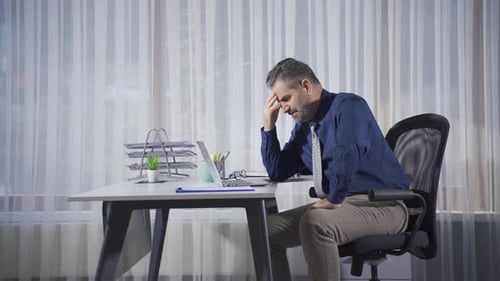 Frustrated Office Worker at Desk with Laptop