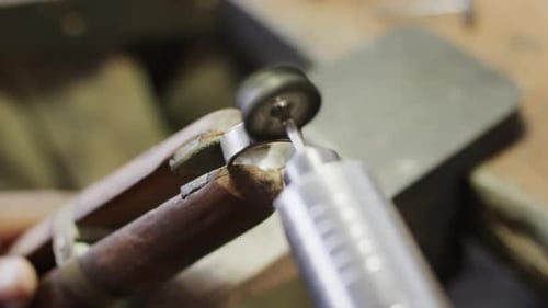 Biracial female worker shaping ring using handcraft tools in workshop in slow motion