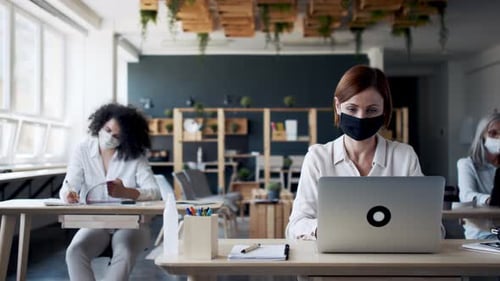 Women Working at Desks in Masked Office Setting
