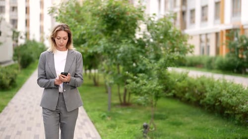 Attractive Lady in Business Suit is Walking in City and Using Smartphone Beautiful Nature of Park