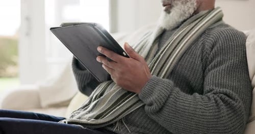 Senior Man Uses Tablet on Cream Sofa