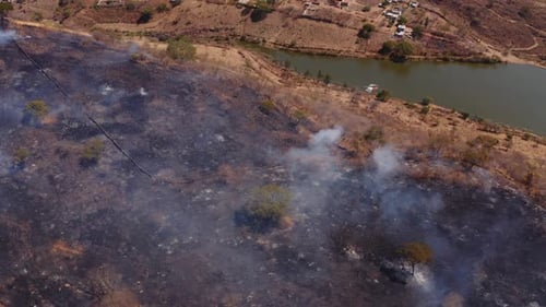 Aerial view overlooking helicopter firefighting forest fire natural disaster on dry grass smoky hill