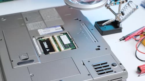 Computertechniker, der einen Akku aus einem Laptop entfernt, Nahaufnahme von Händen, die einen Computer zerlegen
