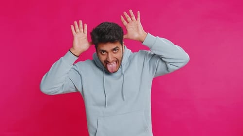 Young Adult Making Faces on Pink Background