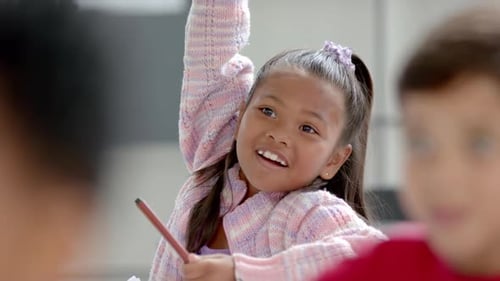 In school, young biracial girl with long dark hair is talking in the classroom
