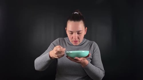 Woman Eating from Bowl with a Spoon Indoors