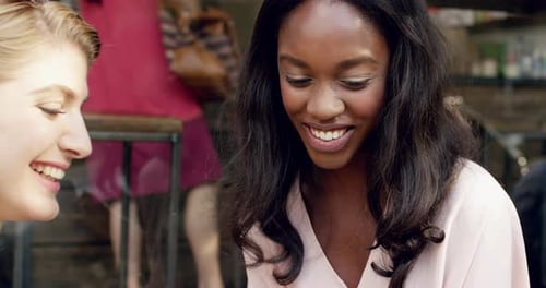 4k video footage of two friends sitting in a cafe together and using a cellphone